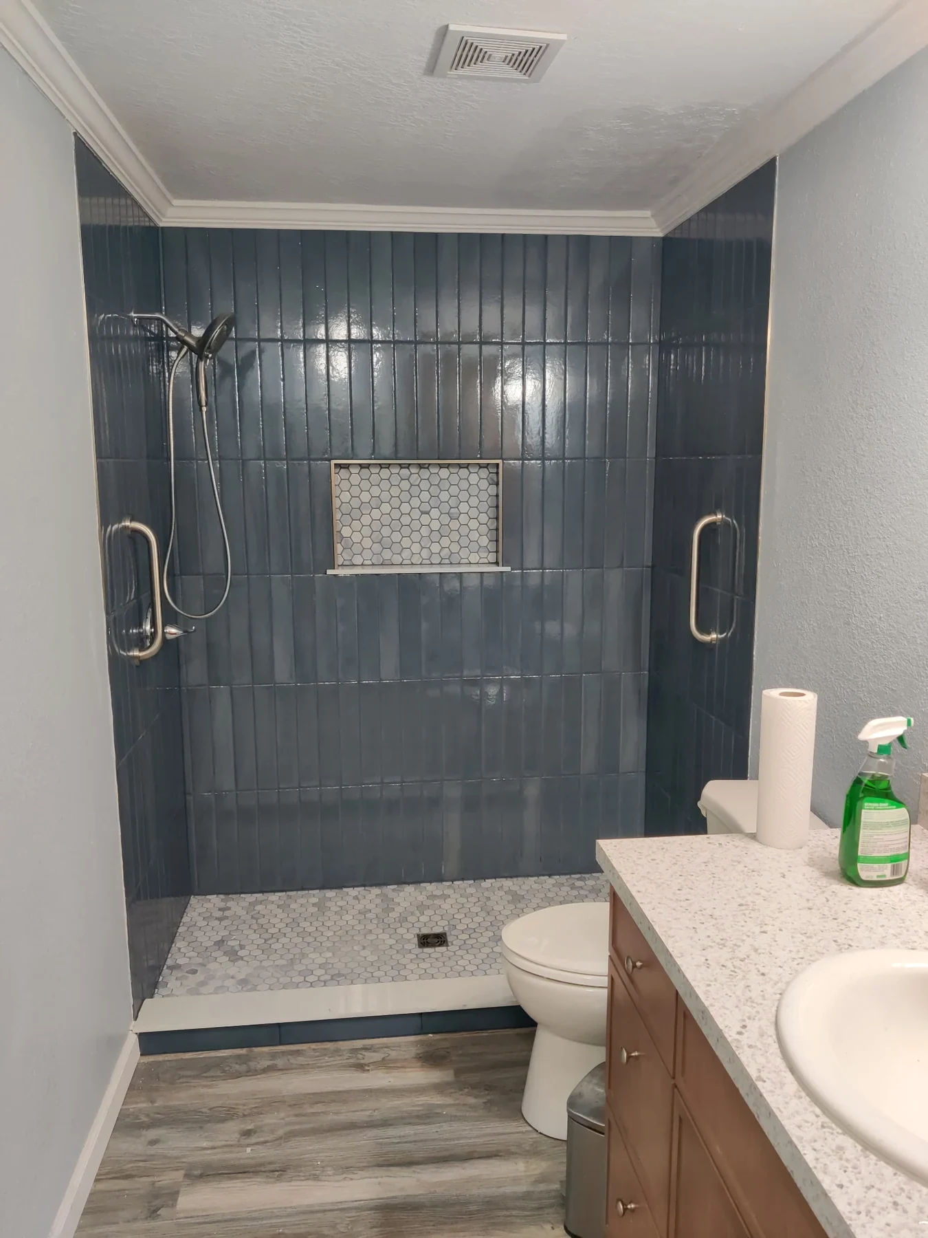 Gray-tile shower with glass enclosure and a light vanity