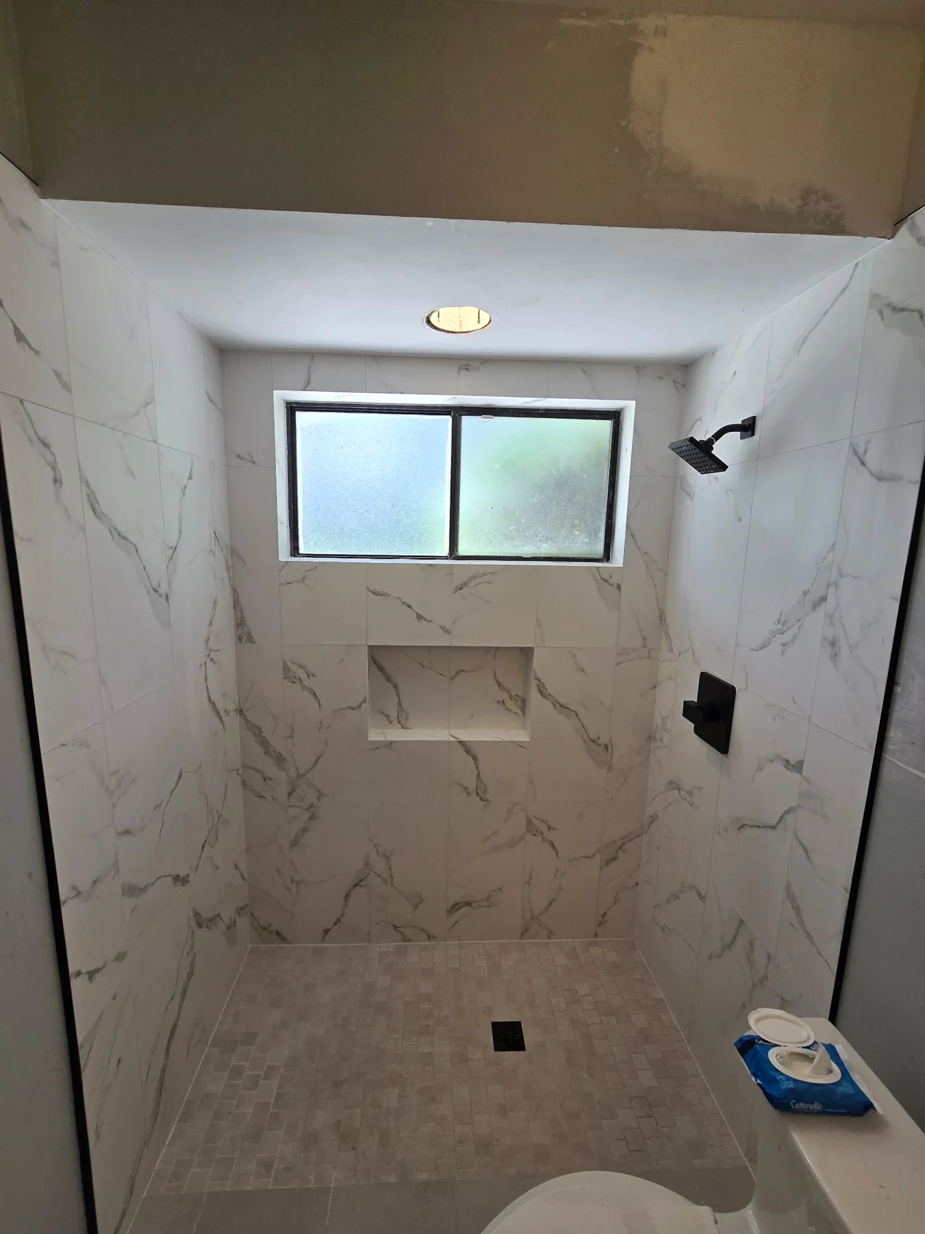 Pale marble-look shower tile with a recessed niche