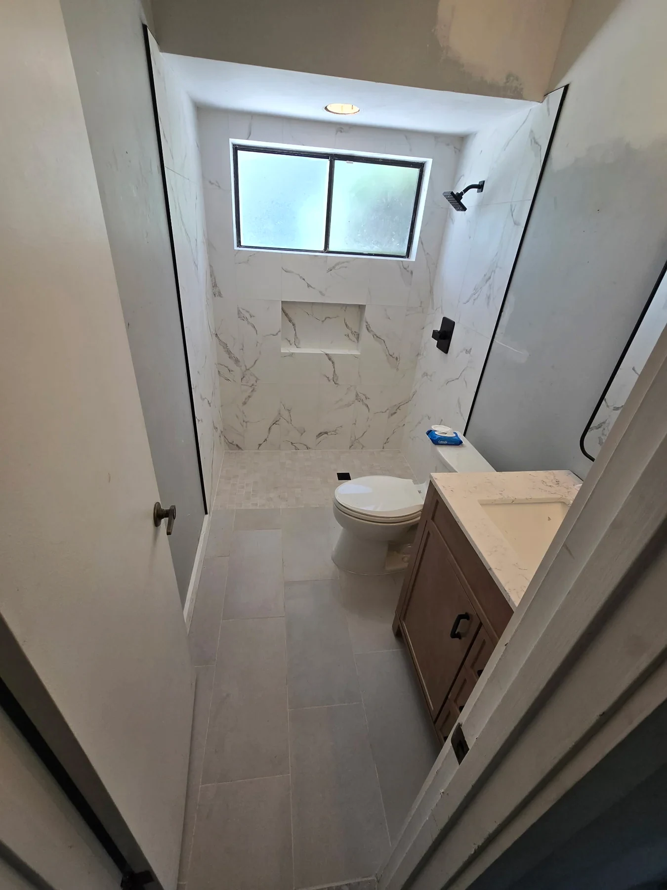 Bathroom with a glass shower, pale wall tile and wood vanity