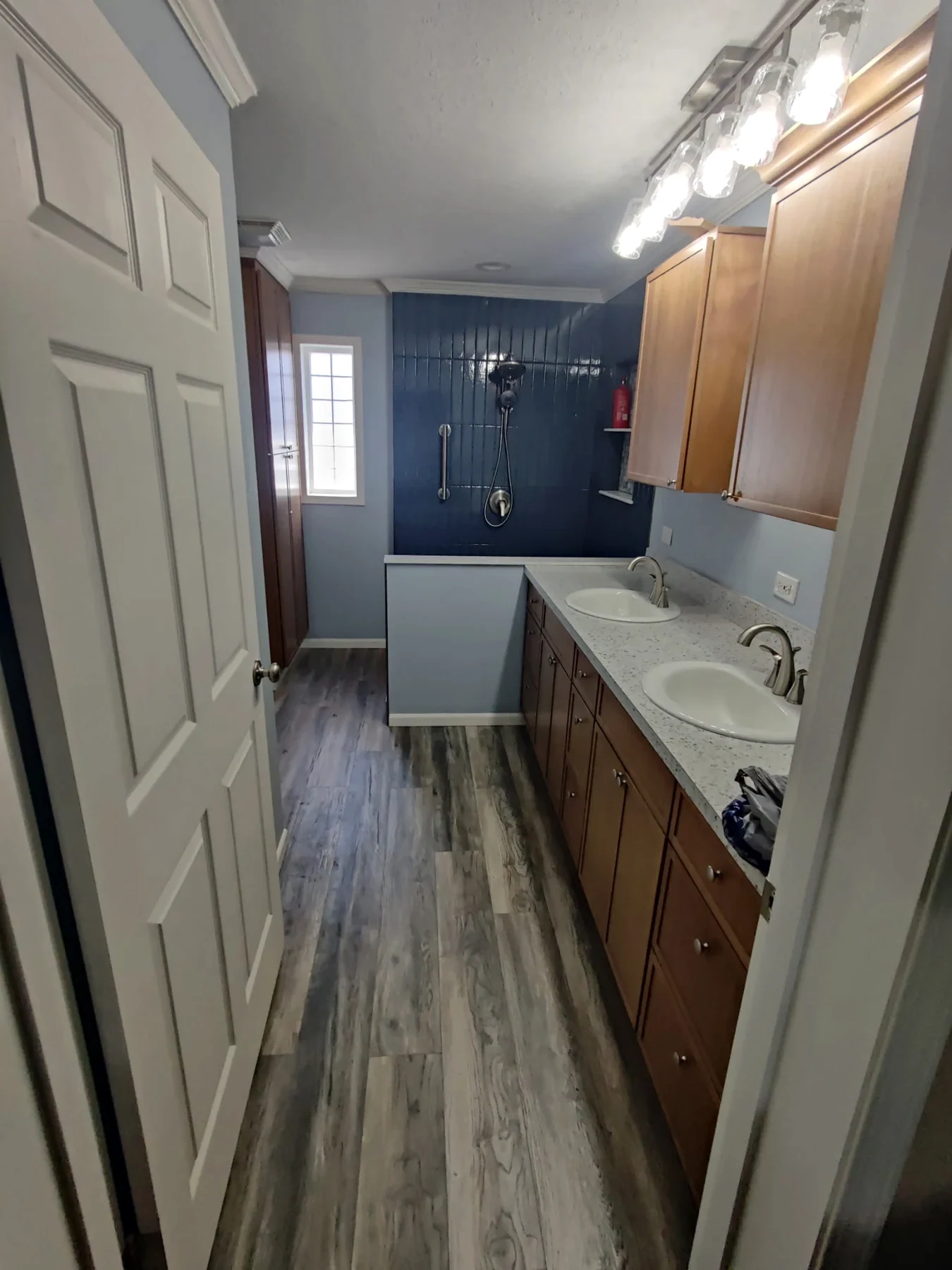 Wood-tone bathroom vanity beside gray tile flooring