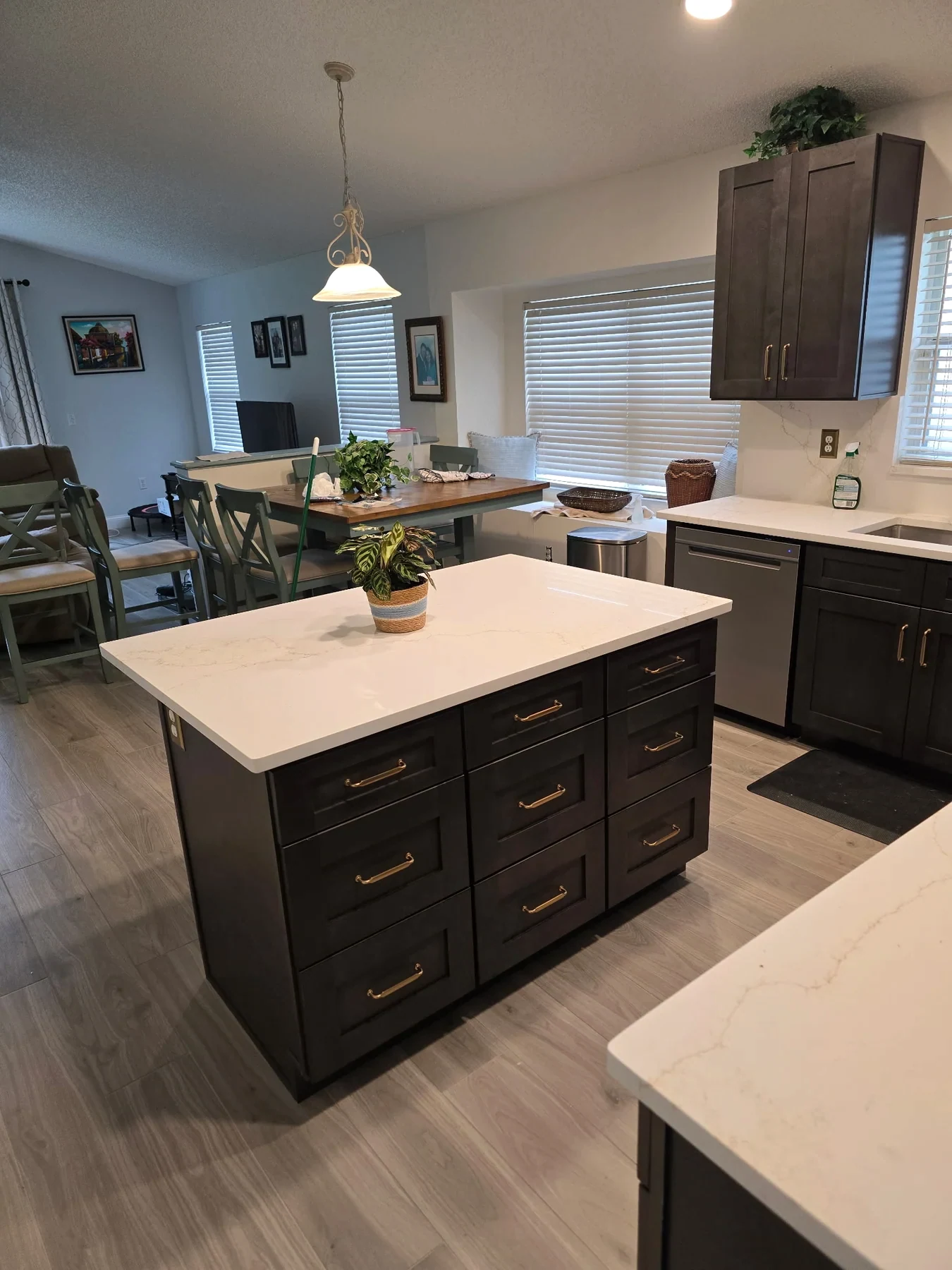 Charcoal kitchen cabinets and a white-topped island viewed from the side