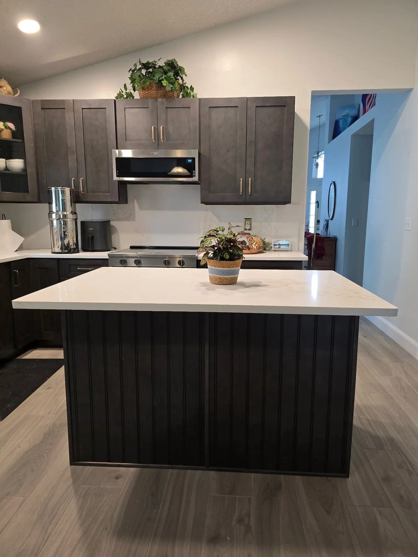 Charcoal kitchen cabinetry, white island countertop and stainless appliances
