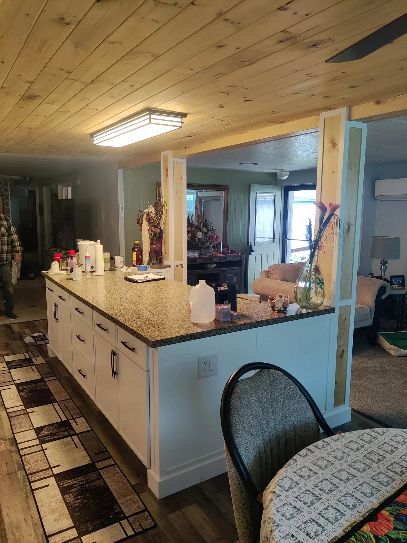 Light kitchen island and cabinetry beneath a wood-plank ceiling