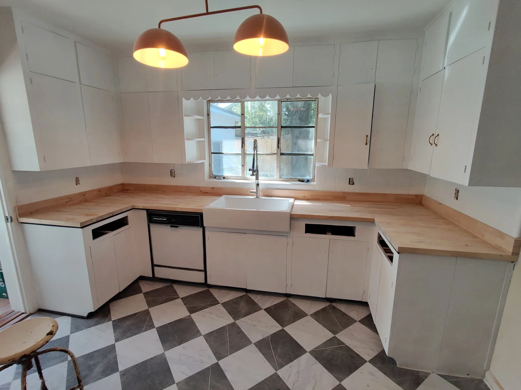 White kitchen cabinetry with wood countertops and a patterned tile floor